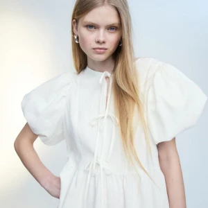 Klänning med puffärm - Säljer denna oanvända, otroliga klänning i linmix med puffärmar. Väldigt bekväm och fin ni till sommaren. Populär och helt slutsåld på hemsidan. Crémevit i färgen. 