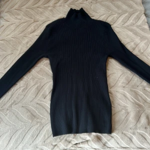 Långärmad polotröja  - En långärmad polotröja i färgen svart. Öppen i ryggen. Helt oanvänd och prislapp sitter även kvar. Köpt på bikbok.