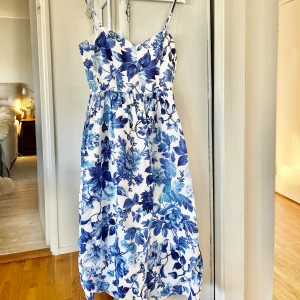 Blommig linneklänning  - Vit och blå blommig linneklänning från H&M. Den är helt oanvänd med prislappen kvar. Storlek S