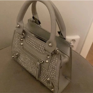 Fin liten ny hand väska med nitar - Säljer denna fina nit nya väska då den inte kommer till användning pågrund av för många andra väskor. Har du någon fråga så svarar jag gärna💕 Pris kan såklart diskuteras☺️