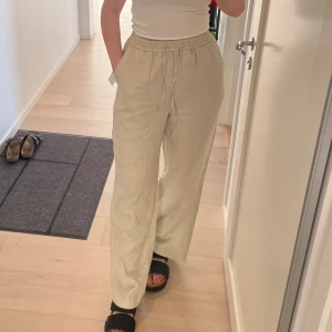 Beiga linnebyxor från NA-KD - Beige linnebyxor från NA-kD, använda några gånger men de är tyvärr för stora för mig. Inköpta förra sommaren. Jag är 168 cm och ni ser på bilden vart byxorna slutar på mig.   Skicket är nyskick. Nypriset är 699kr🤍