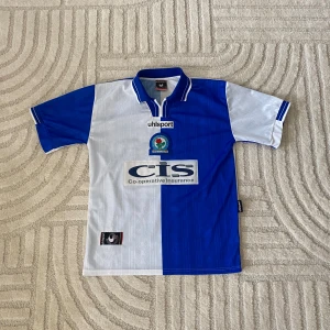 BLACKBURN ROVERS FOTBOLLSTRÖJA  - BLACKBURN ROVERS HEMMA/ 1998-2000  STORLEK: M  PRIS: 549 SEK   OBS! Produkten stryks innan den fraktas iväg. Vid köp eller funderingar kontakta oss.   Instagram: @beyondthekits EJ REPLIKA  #blackburn#rovers#uhlsport