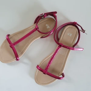 Sandaler rosa H&M 37  - Sommarsandaler i metalik rosa från H&M i storlek 37. Använda ett par gånger men är I fint begagnat skick! 