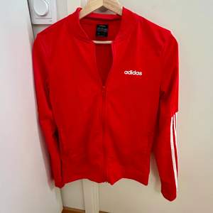 Säljer denna röda adidas zip-up tröjan som aldrig är använd. Det står storlek Xs men jag skulle säga att den är en S. Den är ganska stor på mig som brukar bära S/Xs. Skriv privat för frågor! 