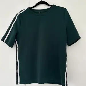En grön kortärmad tröja med svartvit rand längst sidan 