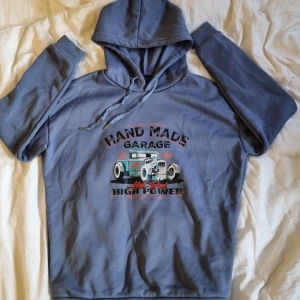 Blå hoodie med tryck  - Blå hoodie med snyggt bil tryck, skönt material, luddig inuti, snören vid luvan. Strl. S 