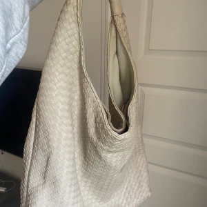 Beige flätad väska från Gina Tricot - Säljer en Bottega Veneta inspirerad väska från Gina Tricot! Har två små svarta fläckar på utsidan och fläckig på insidan men har inte försökt få bort. Annars fint skick! Sista bilden är lånad. 