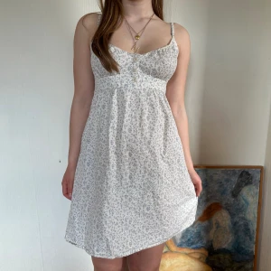 blommig sommarklänning - vit sommarklänning från brandy melville med blått blomster mönster. knytning i ryggen och knappar på framsidan. passar XS-S. skriv för fler bilder eller frågor!