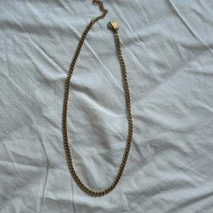 Halsband av en 3 mm bred pansarlänk i 14k Guldpläterat stål. Bredd: 3 mm. Längd: 52 + 8 cm förlängningskedja. Material: Stål. Nypris 399kr. 