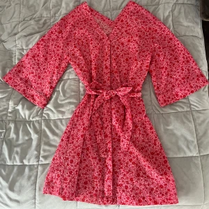 Blommig kimono klänning - Rosa/röd blommig klänning med skärp från Monki💕 storlek XS men eftersom man justerar midjan med skärpet så passar den större och mindre storlekar också🩷 klänningen har några märken och fläckar (se sista bilderna)