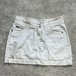 Jeanskjol - Snygg kjol som jag köpte på loppis men typ aldrig har använt.💕 Verkar väldigt använd, inte helt kritvit. Annars inga defekter😄 Midjemått: 39cm, Längd fram: 31cm 
