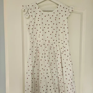 Vit klänning med rosa prickar - Sjukt fin vit klänning med söta rosa detaljer!! Har en fastsydd rosett i ryggen och kanten på kjolen har mesh. Perfekt till sommaren 😍