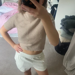 Stickad tröja  - Kortärmad stickad tröja. Ganska tajt passform och slutar under naveln, så snyggt till något lågmidjat. Stretchig i tyget och har halv polo. 