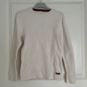 Stickad tröja  - Kräm färgad stickad tröja med röd söm. Aldrig använt 