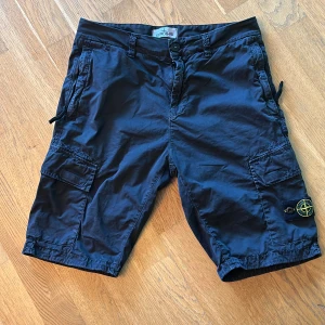 Stone Island Junior 12 år strl 156 - Cargoshorts med kompassmärket. Fint skick! Sparsamt använda Svart tvättad finish. Ny pris ca 2200kr