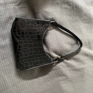 En svart handväska - Säljer en svart handväska med ormmönster på för den inte kommer till användning🩷