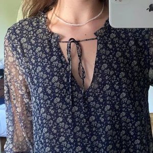 Klänning Mango, strl. M - Supersöt klänning köpt från Mango med knytning samt volang i kragen, på ärmarna och längst ner. Kort modell. Kommer tyvärr inte till användning längre:( Polyestermaterial, fint skick utan anmärkningar.   Hör av dig för fler bilder/frågor ❣️