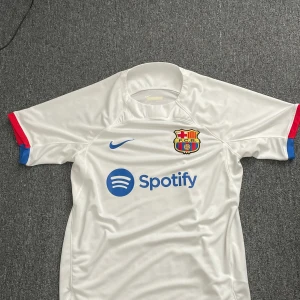 Fc Barcelona tröja  - Säljer min fc barcelona tröja då jag har haft den i 2 månader men har haft på mig den 2-3 gånger men är i toppskick. Tröjan spelades i säsongen 23/24 och det är Ronald aurajo på ryggen. 
