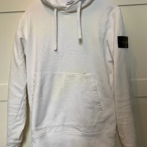 Stone Island Hoodie Vit - Stone Island Hoodie i färgen vit säljes nu k ganska bra skick. Det är en typ av begie nyans av klorin som resultat efter feltvätt på tröjan. Man ser endast detta i vissa ljus. Därmed ett billigare pris på 799kr. Kvitto finns! Storlek Medium