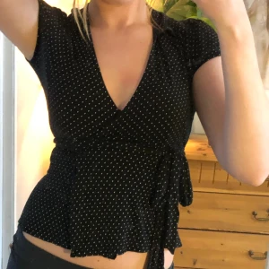 Omlott topp - Söt vitprickig omlott topp med en liten krage som man knyter i midjan. 