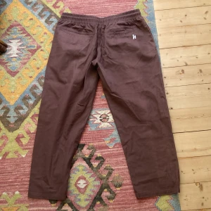 Harlaut Apparel CO. Twill Pants strl. M - Byxor med loose passform från Harlaut Apparel Co. Lite korta för mig som är 178. 100% bomull. Lite lagade över ena fickan. Snörning i midjan och bekväma att ha på sig :) Mycket eftertraktade bland skidåkare ;)