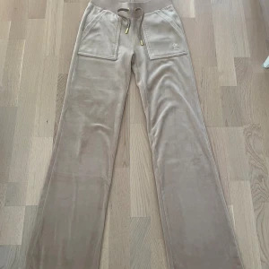 Juicy couture byxor beige🤍 - Jag säljer ett par juicy couture byxor i nyansen beige🥰Jag säljer de pågrund av att de inte kommer till användning längre😔 Knappen är lite sönder så kan därför åka av ibland men det är bara att sätta på igen🥰 Köpta för 1200🥰Köparen betalar frakten💕