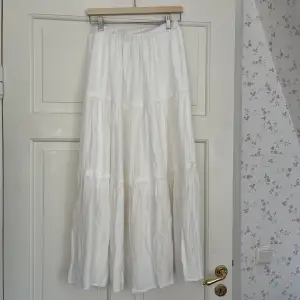 Lång vit kjol i mjukt men ganska tungt/rejält material. Underkjol. Spetsdetaljer. Räcker till anklarna på mig som är ca 168 cm. Köpt second hand i nyskick, använd endast en gång av mig. Supersnygg och trendig till sommaren! Passar xs-m tror jag. 