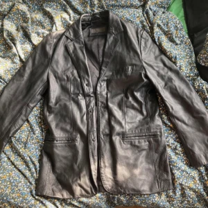 svart skinnjacka äkta läder  - svart, vintage skinnjacka köpt second hand för ca ett år sedan. den är äkta läder och köptes för 750kr. inga defekter och väldigt bra skick. Är en herrjacka men funkar för vem som. Storlek S. Pris kan diskuteras!