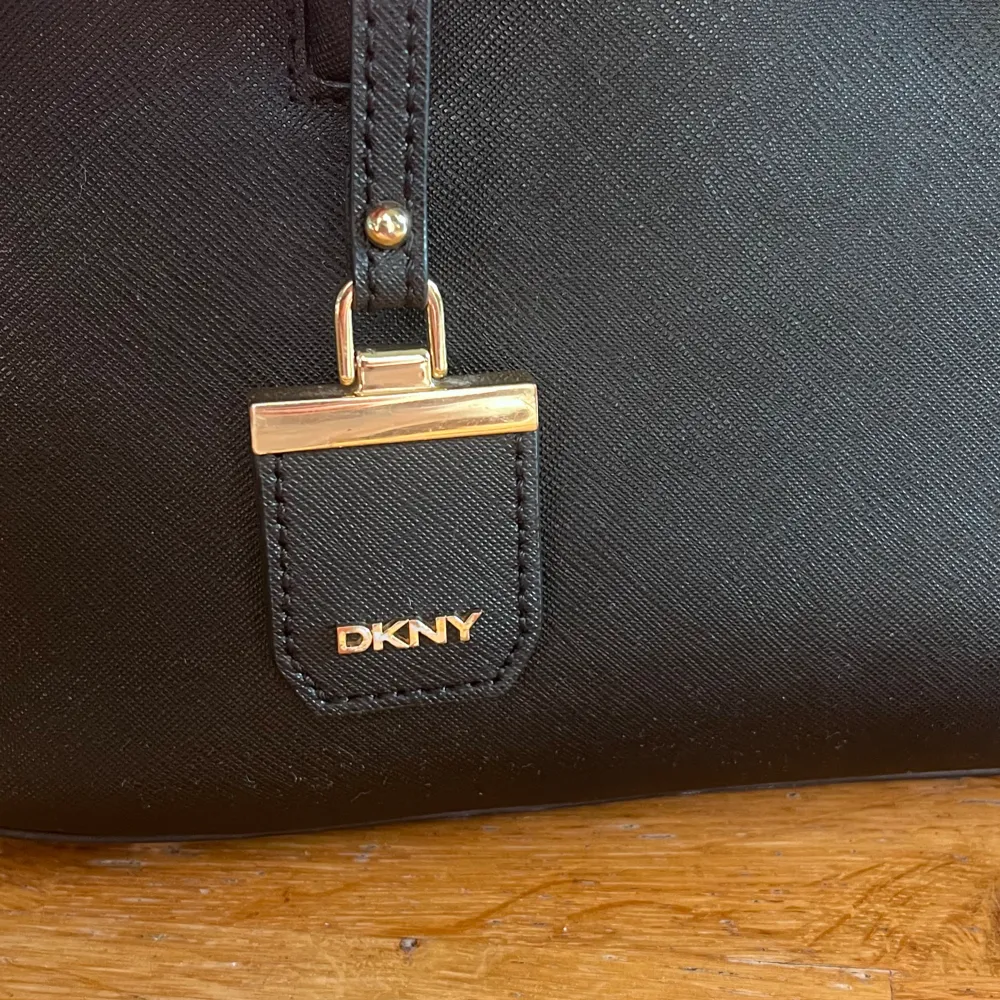 Äkta DKNY väska som är köpt på NK 2020, därav finns inte kvittot kvar. Ny pris 3500 kr. Äkta läder med guld detaljer på drag kedja osv. axelrem ingår!19 cm på höjden, 29 cm längd och 12 cm bredd. väskan är ni ny skick och priset kan diskuteras!💕🙏🏽. Väskor.