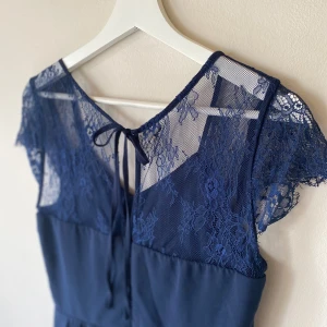 Marinblå långklänning från Vila i strl. 38 - En jättevacker långklänning från Vila som tyvärr inte passade mig. Klänningen är marinblå och har vackra spetsdetaljer på ryggen. Klänningen är maxilång och i storlek 38 (M).