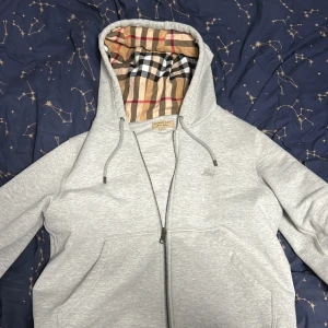 Burberry grå zip hoodie - Populär Burberry kofta i grå, Skick 10/10 inga skador eller fläckar, Priset är ej hugget i sten storlek M, kan funka S också om man inte är för krallig. Priset är ej hugget i sten men överdriv bara inte då den är redan extremt nedsatt