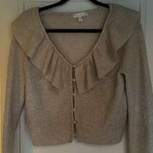 Stickad tröja  - Stickad tröja med volanger och knappar framtill. Från h&m. Fint skick. Varm och go. 