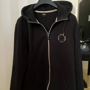 Hugo Boss Zip - Nypris 3000. Storlek L men passar M. OK skick, lite bokstäver som lossnat som syns på bilden. Liten väska följer med om så önskas. 