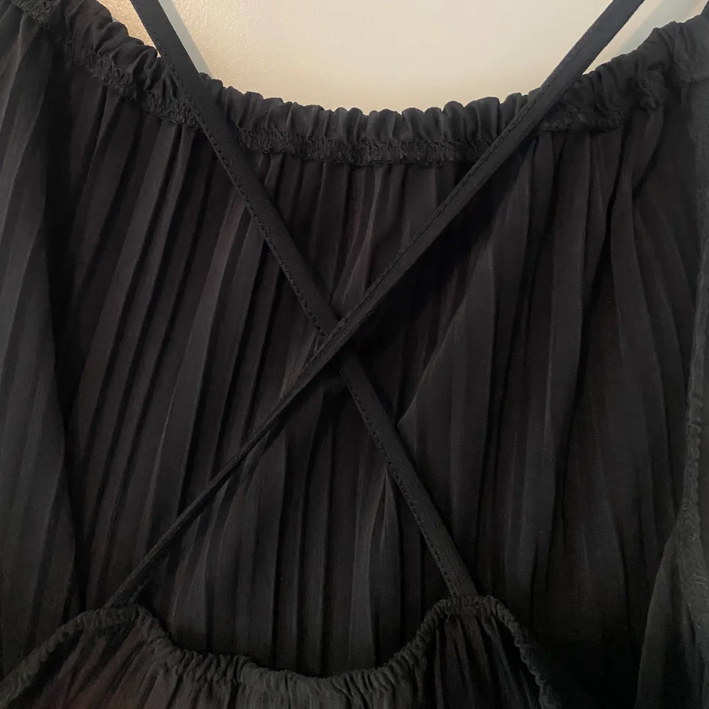 Oanvänd. Denna tröja är från Bianca Ingrosso kollektion med Gina tricot, modellen är ”Tamara singlet”. Plisserat linne med tunna axelband som korsas i ryggen. Linnet är svart och har rynkade detaljer vid halsringningen. Denna tröja säljs inte längre.. Toppar.