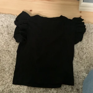 Volang tröja  - Jag säljer denna svarta volang tröjan från Gina Tricot i svart i st 158/164 den sitter jätte fint på och är i ny skick 👌🏻👌🏻🥰