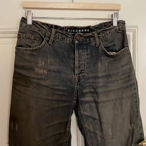 jeans i blåbrun färg med slitningar, uppsydda. midjemått: 84 cm, innerbenslängd: 70 cm