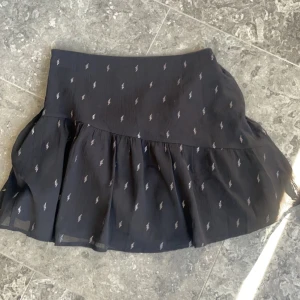 Svart kortkjol  - Svart kort volangkjol med silver detaljer 