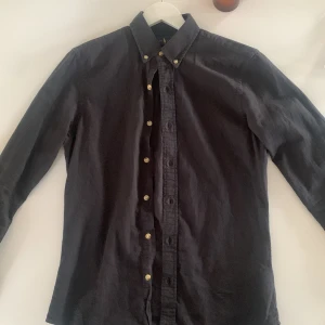 Ralph lauren skjorta - Säljer denna svarta Ralph Laoren skjorta då den börjar bli lite liten för mig. Skick 9/10. Pris 449kr