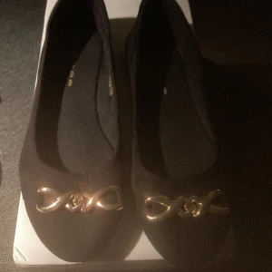 *NY*Svart ballerinaskor i Stl 36 Fr din sko  - I konstmocka med snygg detalj i guld. Nya och oanvända. Ngn rynka kan finnas pga förvarats i kartong men rätar ut sig direkt igen på foten. Inget att anmärka på. 