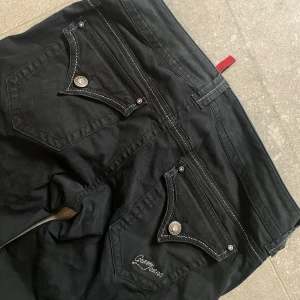 guess vintage lowwaist straightleg jeans med detaljer och fickor - Innerben:80cm. Midja:37 cm. FRÅN GUESS! Strl w28/S! Så snygga men tyvär för små. Fint skick (har en liten fläck på ena benet men går säkert att få bort med fläckborttagning).skicka gärna prisförslag på lägre pris eller använd köp nu!💋