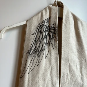 Hobo bag med motiv - En hobo-bag/crossbody totebag jag sytt själv. Är amatör så ingen garanti på hållfastheten eller sömmarna🥲. Har ritat motiv med en vinge på axeln så det ser ut som att man har en när väskan är på. Ritat med bläckpenna aka inte vattenfast🩷
