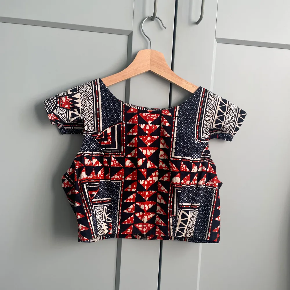 Beautiful wax print set in navy and orange colors. Handcrafted Top features a unique cap sleeve and crop boxy silhouette. Back Zip Closure. Matching Pants Sold Separately  100% Cotton  Best Fits Size XS. Blusar.