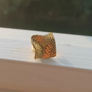 Guldfärgad ring - En guldfärgad ring med en unik, texturerad design. helt oanvänd. justerbar storlek 