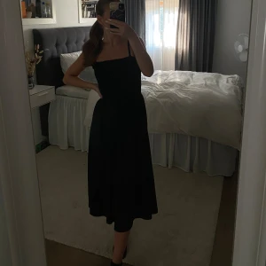 Svart klänning - Svart klänning med ribbat upptill och ett flowit material nertill. Klänningen är använd 2-3 gånger för några år sedan. Justerbara band finns. Väldigt stretchigt material och skön att ha på sig.