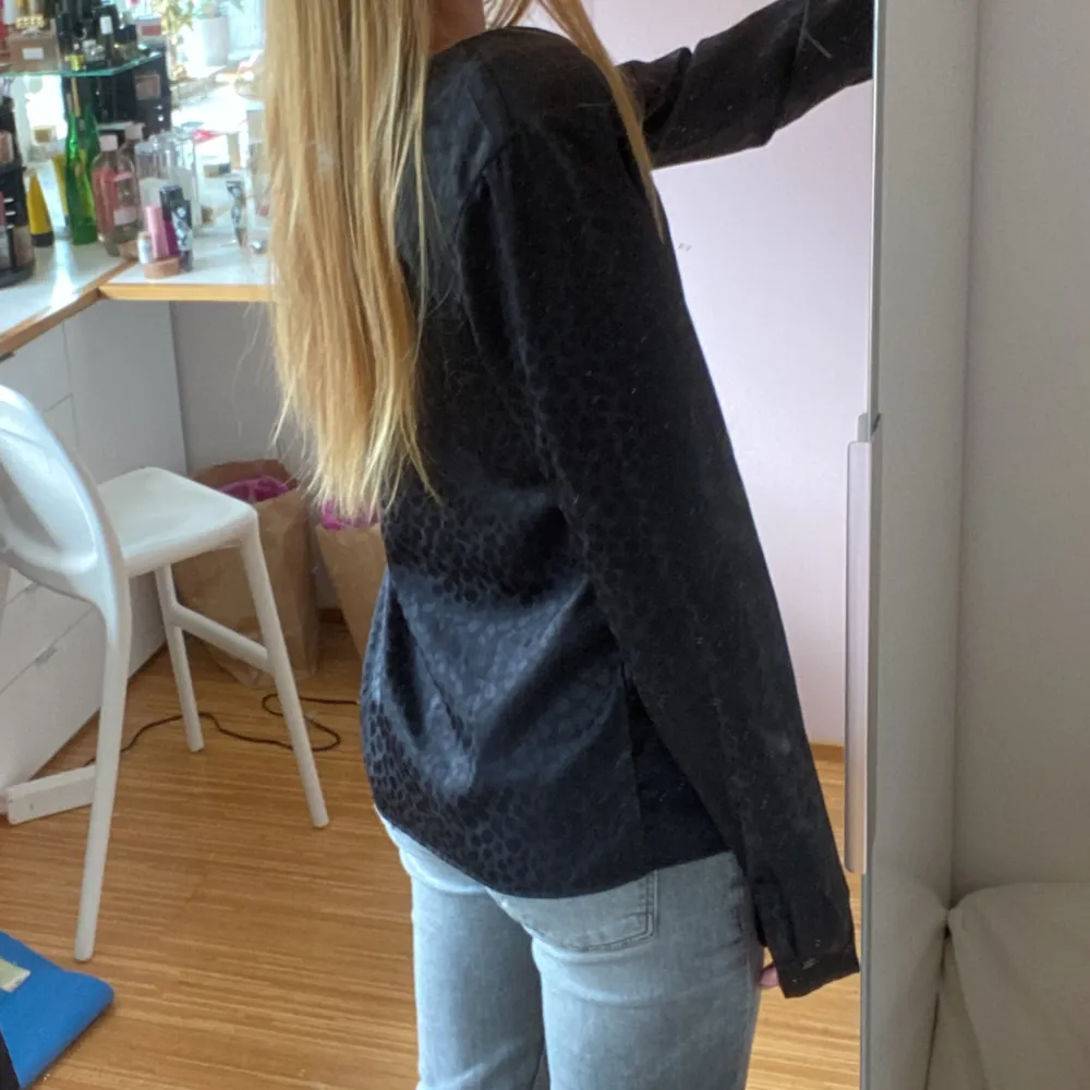 En elegant svart blus från VILA med ett leopard 🐆 mönster. Blusen har långa ärmar och en v-ringad hals. Den är tillverkad i ett lätt och bekvämt material. 🩷. Blusar.