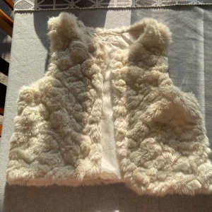 Päls jacka - En mjuk och fluffig beige pälsväst från H&M. Västen är ärmlös och har en bekväm passform, perfekt för att hålla värmen under kyliga dagar. passar perfekt för att ha den över en klänning eller topp, väl använd men inga defekter finns, är stor i strl så passar från xxs till s, jätte gullig💗