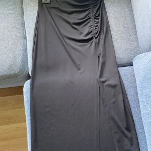 Svart kjol med slit - Svart medellång kjol, går till typ mitten av smalbenen. Har en slit på vänstra sidan och typ scrunch ovanför, superfin. Köpt på Gina Tricot för två år sen för skolavslutning men knappt använd efter det. 