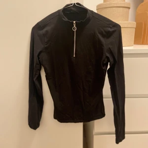 Svart tight  lång armad tröja med kedja vid halsen  - Svart, tight, långarmad,  47cm lång  30 cm bred vid byst 