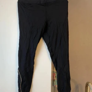 Svarta leggings - Ett par svarta leggings med hög midja. De är tighta och har en enkel design utan mönster eller detaljer.