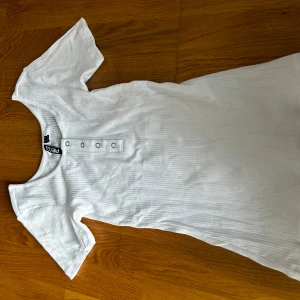 Topp med knappar - T-shirt topp med knappar köpt från Nelly men från pieces. Aldrig använd.